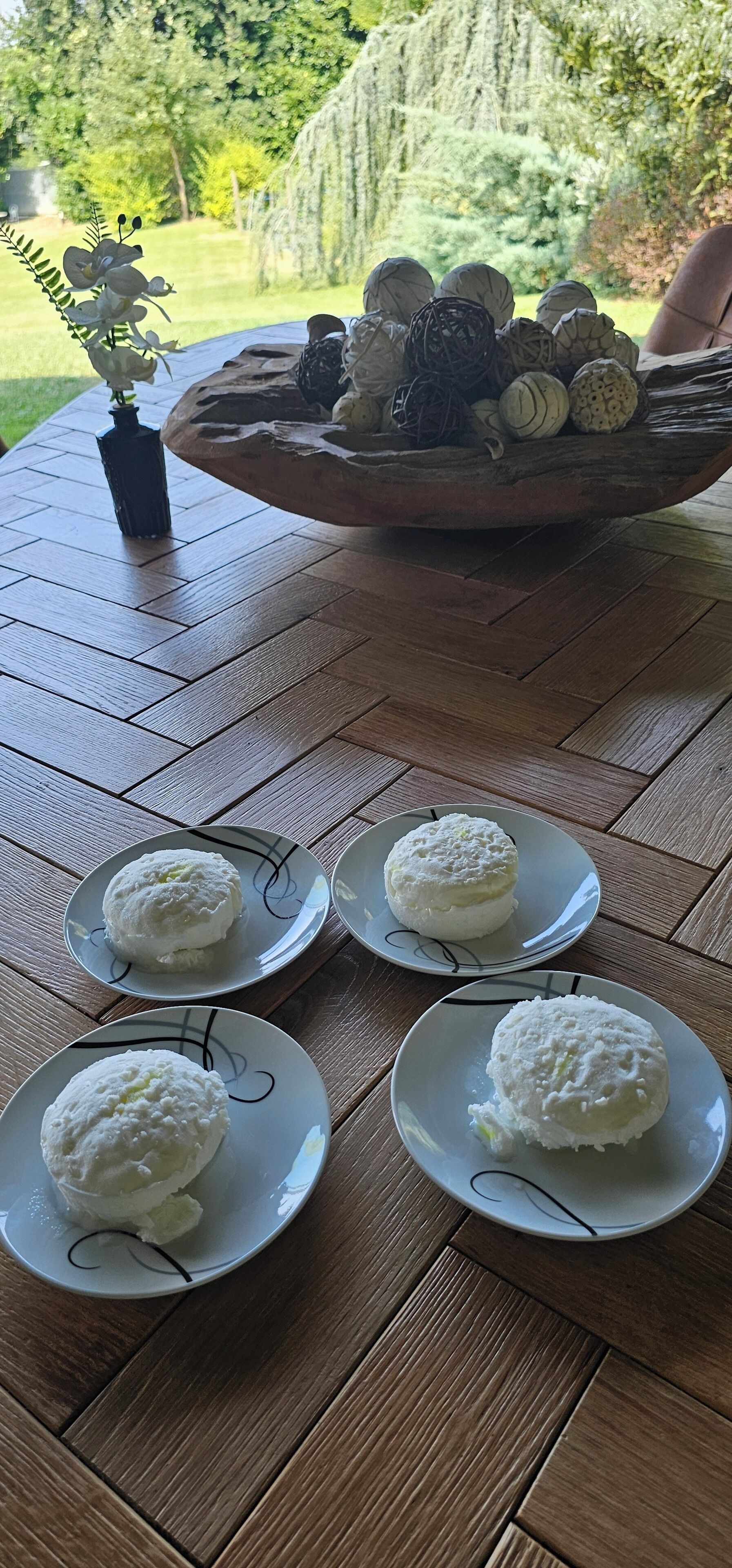 Una mesa con cuatro platos de albóndigas blancas, un jarrón con flores y un recipiente con diversos objetos.