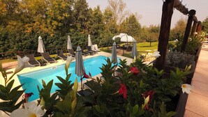 A pool area with lounge chairs, umbrellas, and a gazebo. - Villa Fonte  (Ferrere)