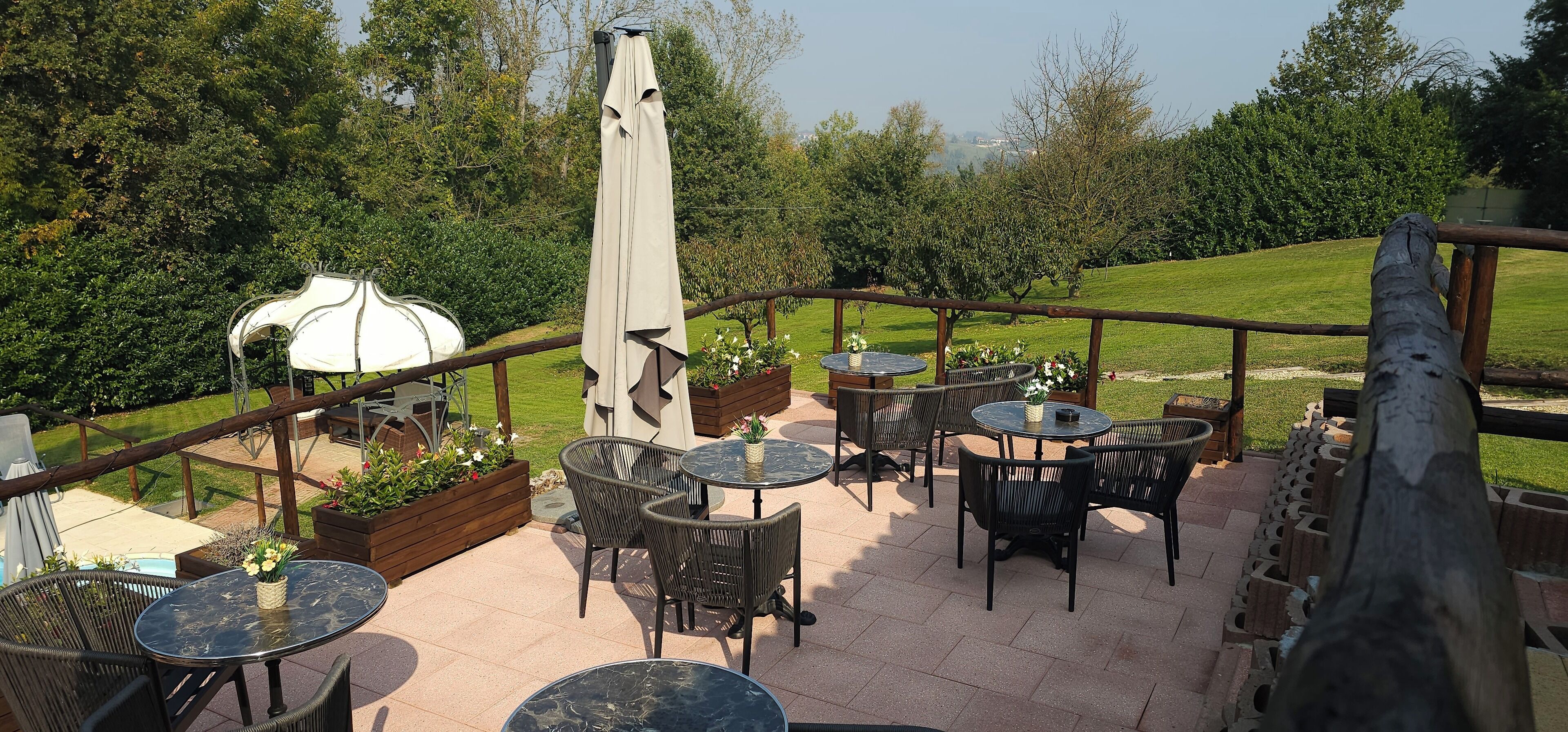 An outdoor patio area with round tables and chairs, a barbecue grill, and a white water tank.