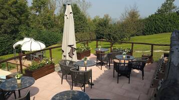 An outdoor patio area with round tables and chairs, a barbecue grill, and a white water tank.