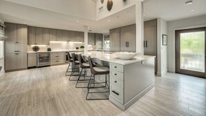 Una cocina moderna con una isla grande, taburetes de bar y un techo decorativo.