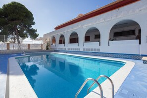 Ein Swimmingpool mit einem weißen Gebäude, das Rundbogenfenster und ein Ziegeldach aufweist.