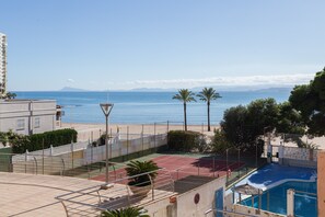A residential area with a tennis court, a swimming pool, and a view of the sea.