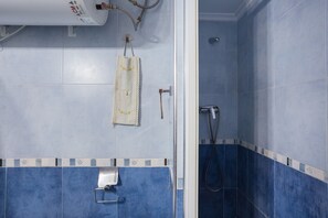 Ein Badezimmer mit blauen Fliesen, einem Handtuchhalter, einer Handbrause und einem Handtuchspender.