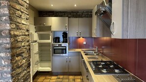 Eine moderne Küche mit Backsteinwand, Edelstahlgeräten und Holzausstattung.