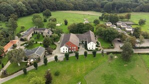 Eine Luftaufnahme einer ländlichen Gegend mit mehreren Häusern, einem großen Feld und einem kleinen Gewässer.
