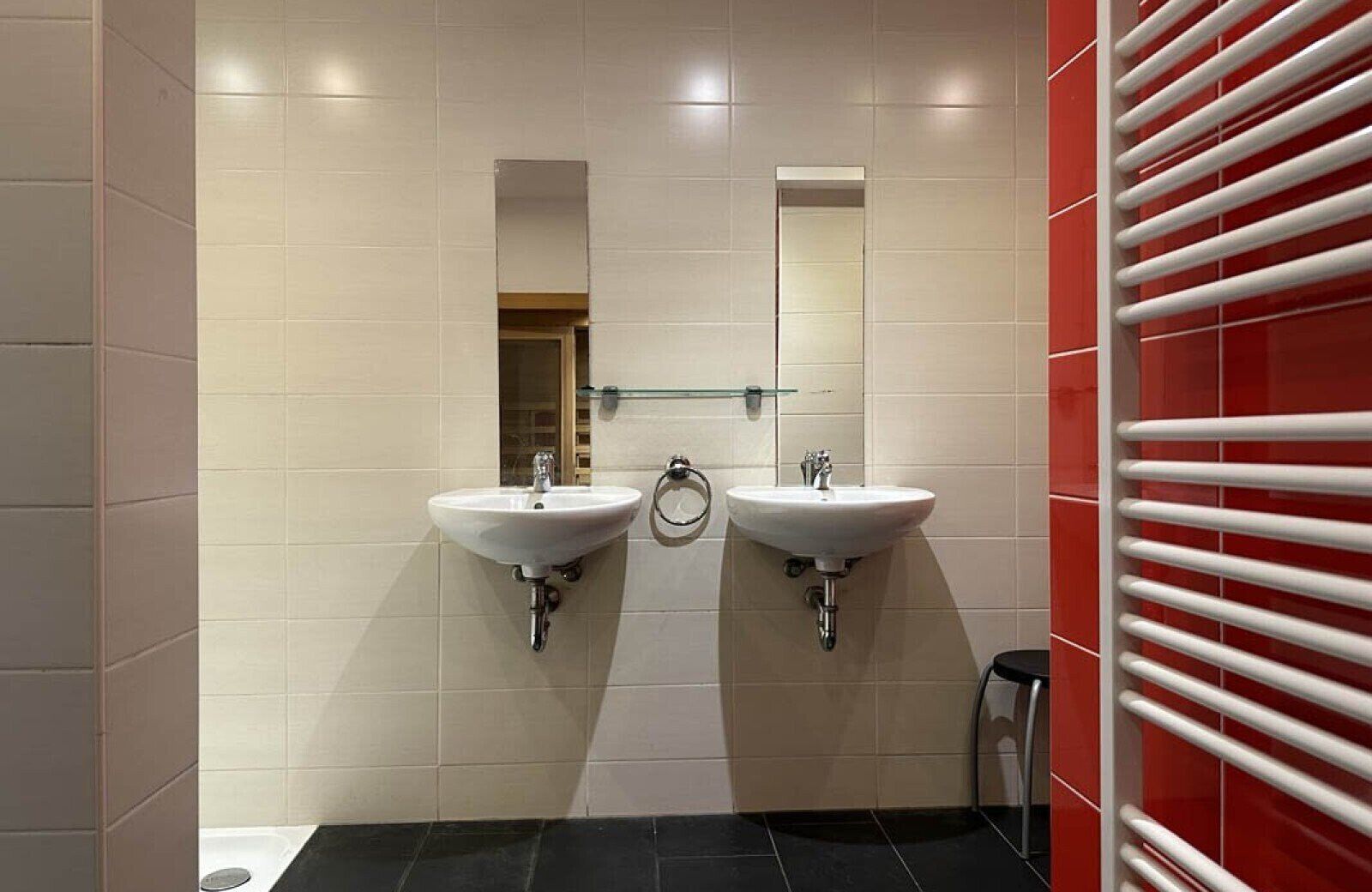 Des toilettes équipées de deux lavabos, d’un miroir et d’un porte-serviettes.
