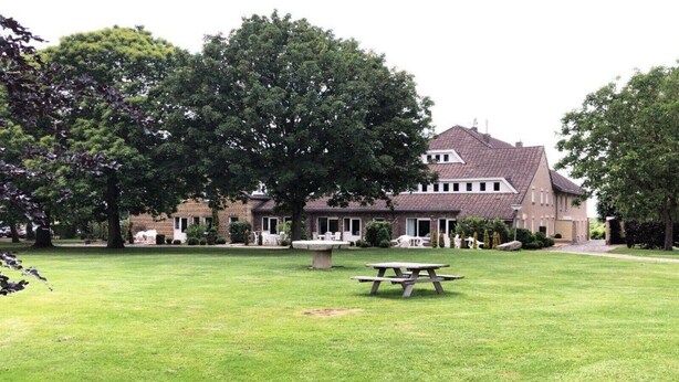 A large building with a well-maintained lawn and a picnic table in the foreground.