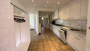 A modern kitchen with white cabinets, a stainless steel sink, and a tiled floor.