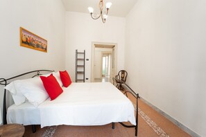 A bedroom with a bed, red pillows, a chandelier, a painting, a ladder, and a chair. - A Casa di Antonio by Wonderful Italy (Naples)