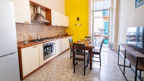 A kitchen with white cabinets, a stove, and a dining area with a table and chairs.