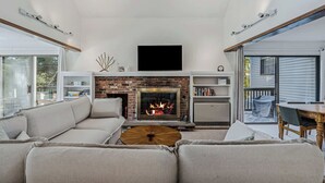 Ein Wohnzimmer mit Kamin, einer Couch, einem Couchtisch und einem Fernseher.