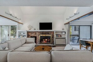 A living room with a fireplace, a sofa, a coffee table, and a television.