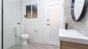 Et badeværelse med toilet, vask, spejl og et vindue.