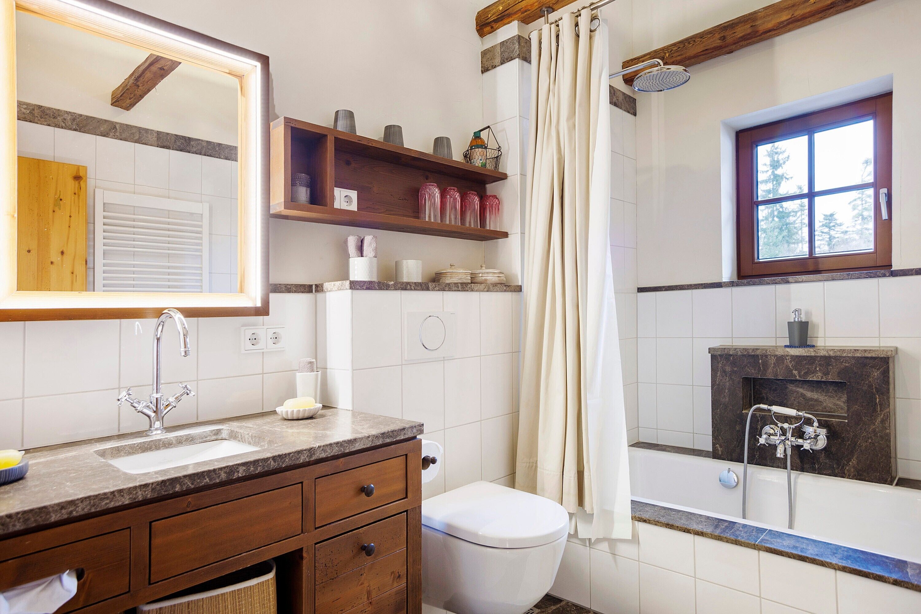 A bathroom with a sink, toilet, shower, and a window.