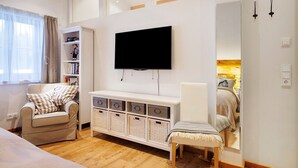 Un saló modern amb televisió de pantalla plana, un sofà, una cadira, una biblioteca i un mirall gran.