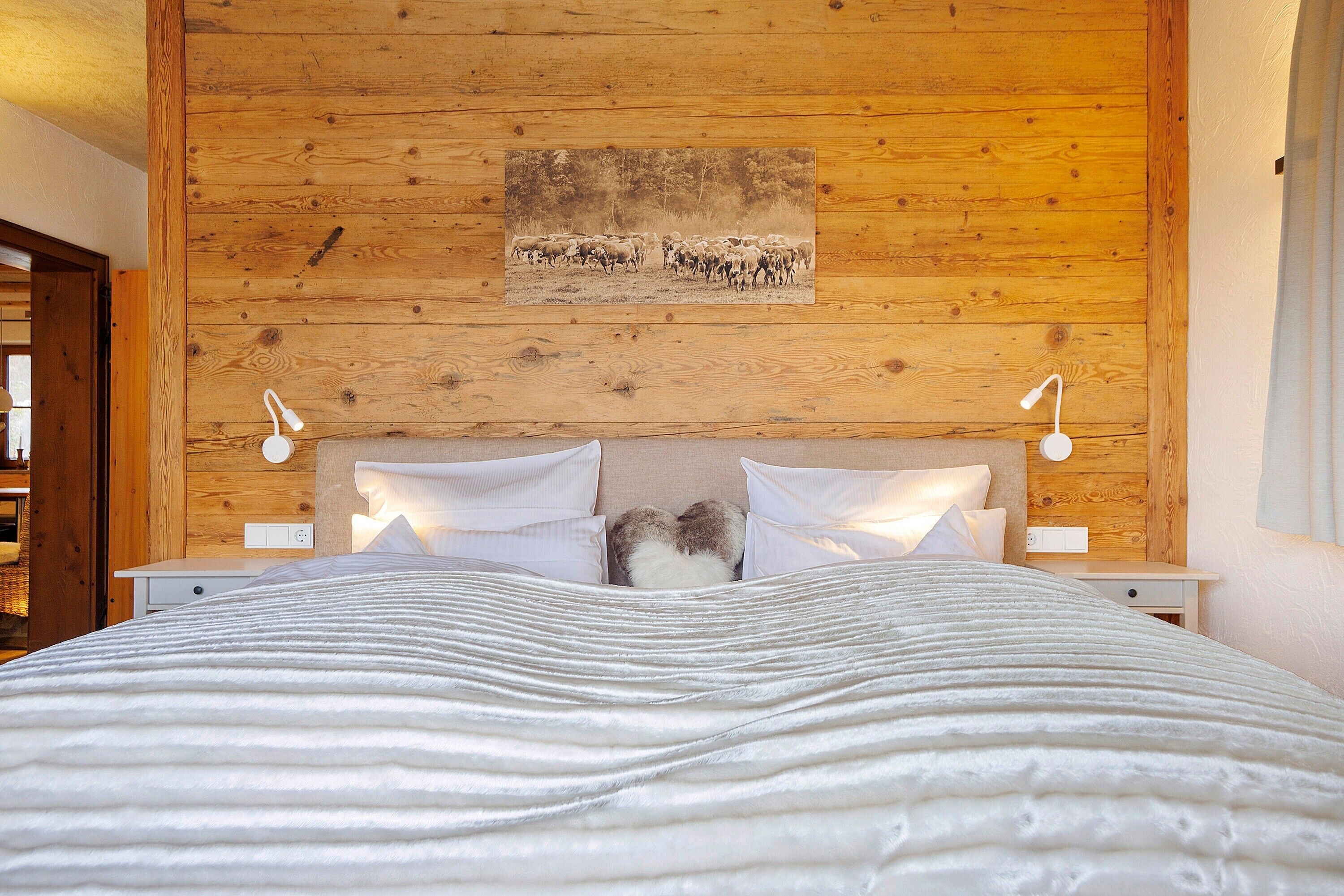 A wooden-paneled bedroom with a bed, pillows, and two bedside lamps.