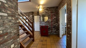 A staircase leading to a room with a brick wall, a wooden bench, a red cabinet, and a white door. - Bungalowpark Landsrade - Vrijstaande bungalow 10 (Gulpen)