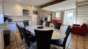 A modern kitchen with white cabinets, a central island, and a dining area with a round table and chairs. - Bungalowpark Landsrade - Geschakelde Bungalow 9 (Gulpen)