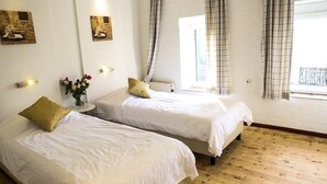 A hotel room with two beds, a wooden floor, and a window with curtains. - Bungalowpark Landsrade - Geschakelde Bungalow 9 (Gulpen)