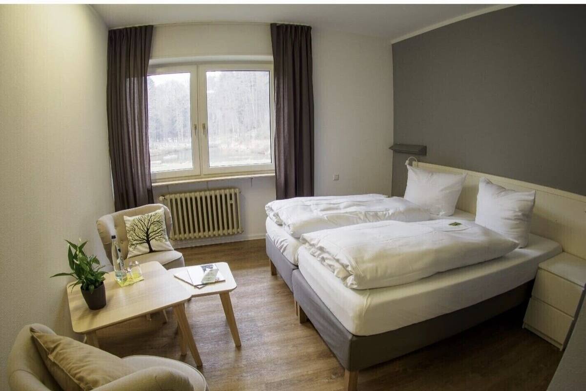 A hotel room with a bed, a desk, a chair, and a window with curtains.