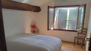 A bedroom with a bed, a chair, a window with a view, and a lamp.