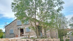 A stone house with a stone wall, a wooden door, and a small porch.