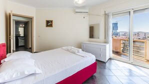 A hotel room with a bed, a vanity with a mirror, and a balcony with a city view. - Spacious Stay in the Heart of Tirana by PikHost (Tiranë)