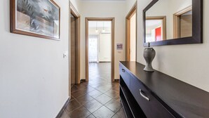 A hallway with a dark wooden dresser, a large mirror, and a framed painting on the wall. - Spacious Stay in the Heart of Tirana by PikHost (Tiranë)