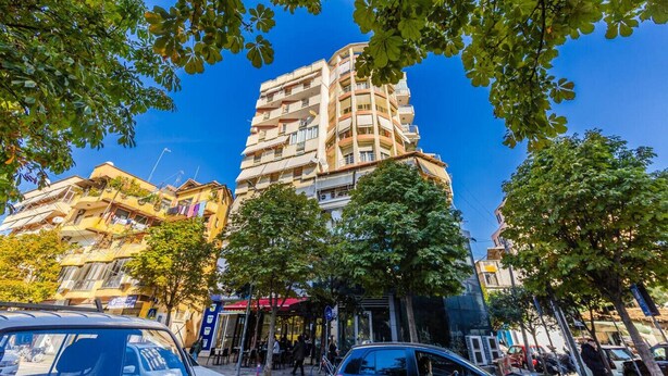 A multi-story building with balconies, surrounded by trees and parked cars. - Spacious Stay in the Heart of Tirana by PikHost (Tiranë)