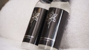 Two bottles of shower gel and conditioner on a white towel. - The Old House 1147 (Maesteg)