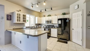 A modern kitchen with white cabinets, a granite countertop, stainless steel appliances, and a clock on the wall. - Labor Day Weekend Special: Flexible Check-in/out! (Phoenix)
