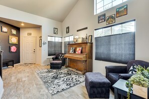 A spacious living area with a piano, comfortable seating, and artwork on the walls. - Relaxing Phoenix Home - Outdoor Entertainment Area (Phoenix)