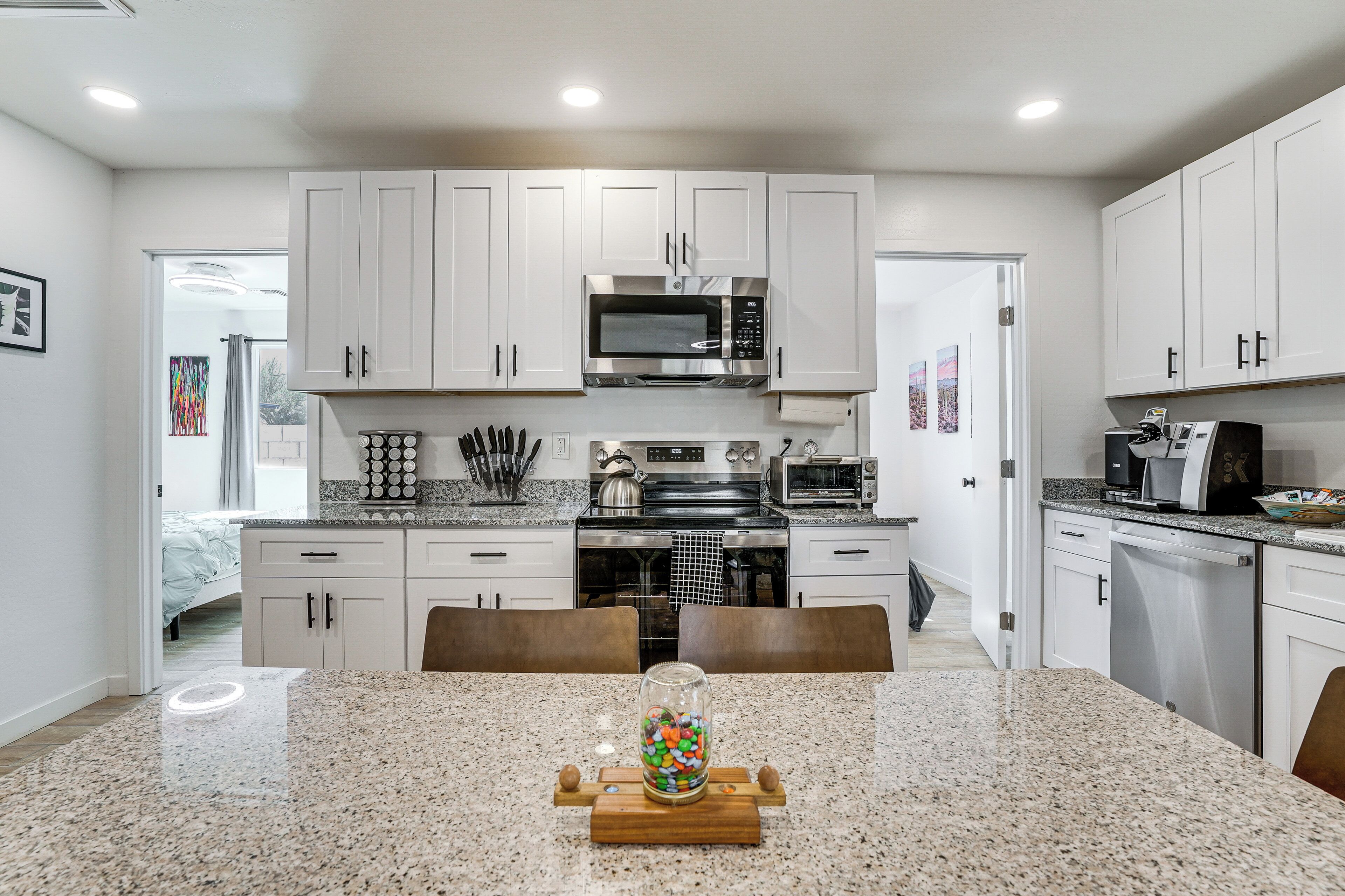 A modern kitchen with white cabinets, stainless steel appliances, and a granite countertop.