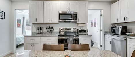 A modern kitchen with white cabinets, stainless steel appliances, and a granite countertop.