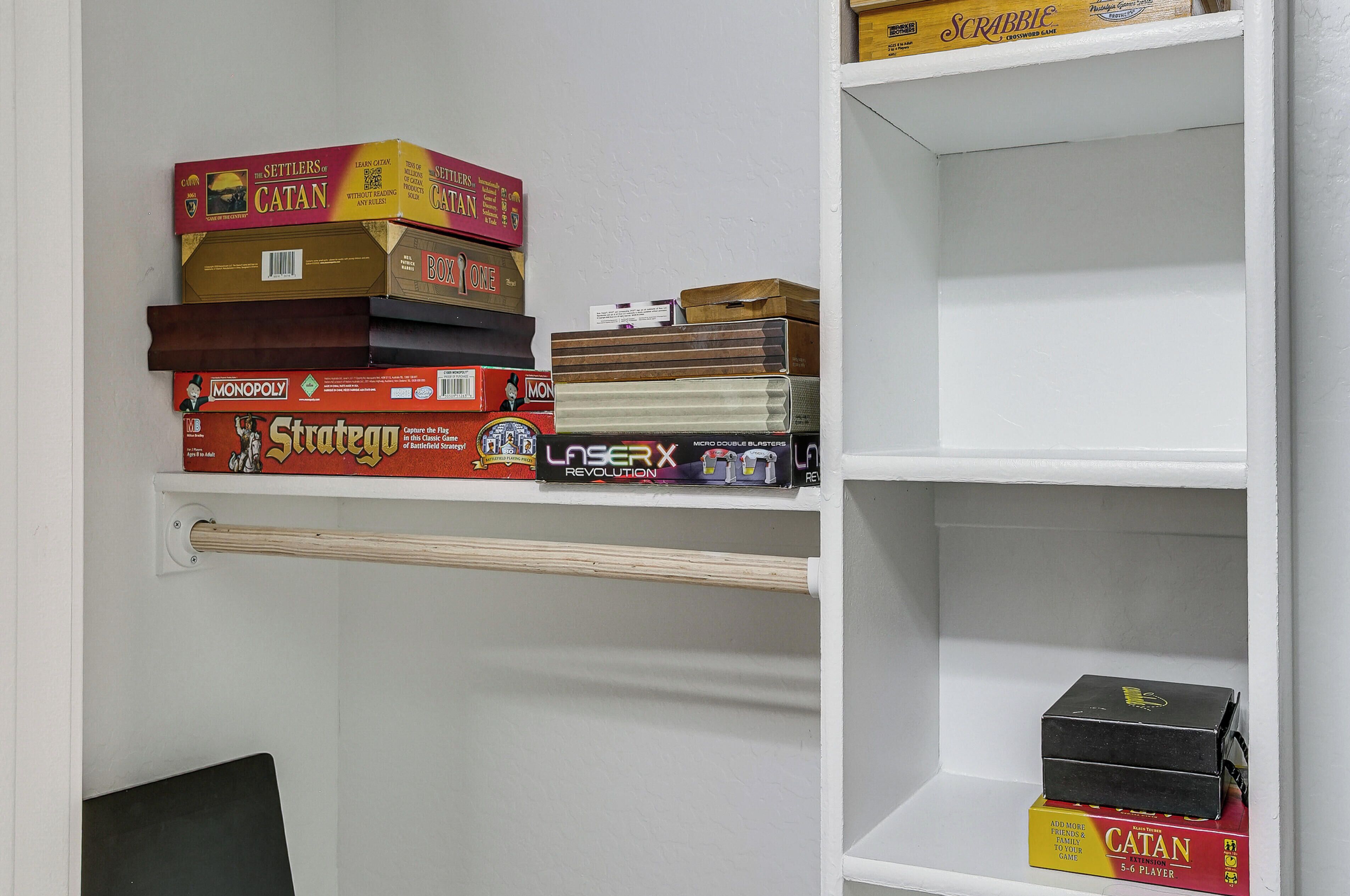 Een plank met verschillende gezelschapsspellen, waaronder Settlers of Catan en Monopoly.