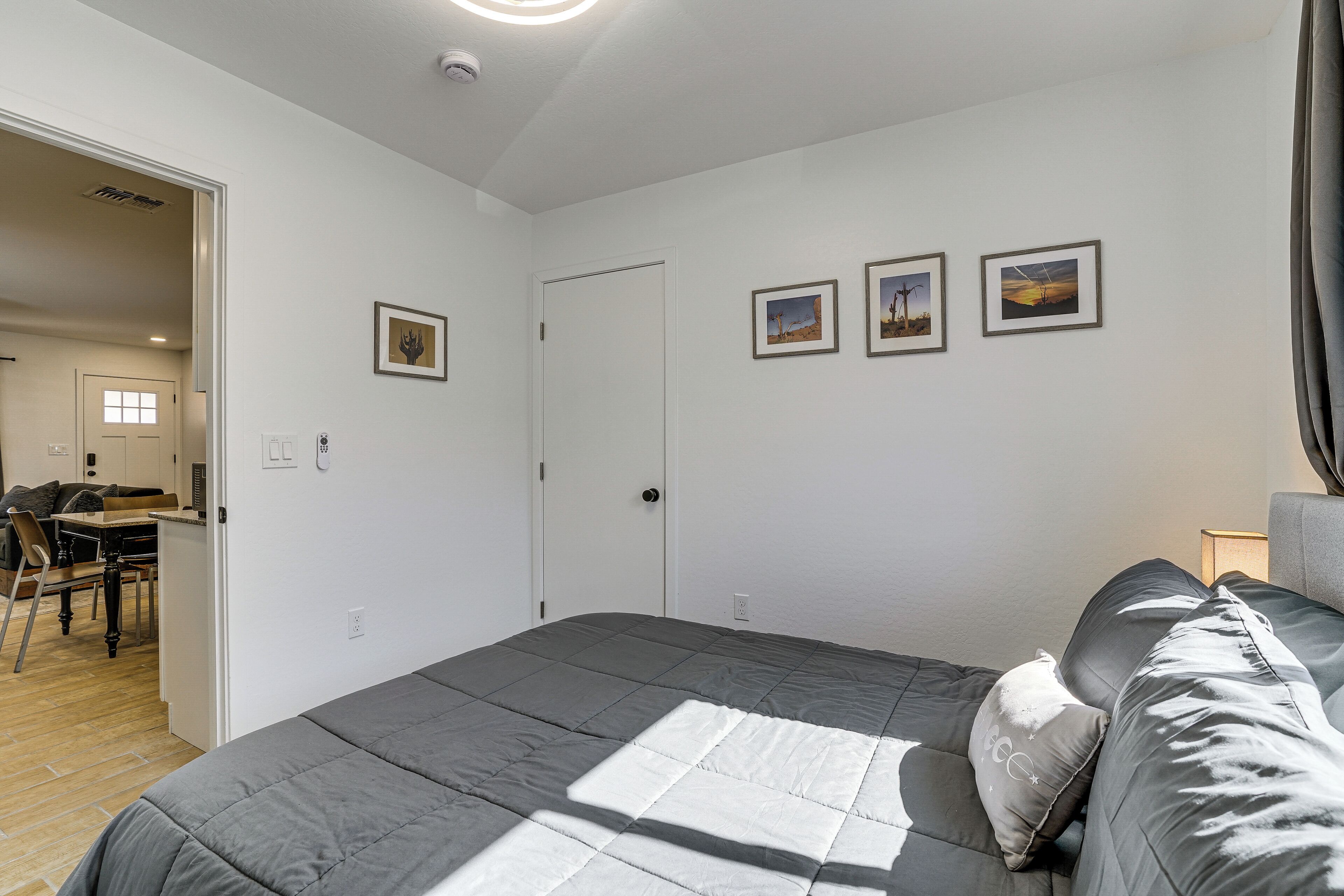 A bedroom with a bed, a door, and three framed pictures on the wall.