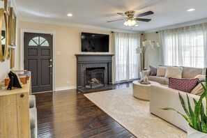A living room with a fireplace, a sofa, a coffee table, and a television mounted on the wall.