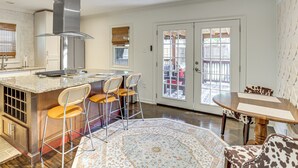 A modern kitchen with a central island, bar stools, a dining table with chairs, and a patterned rug. - 1 Mi to Smu: Home w/ Outdoor Entertainment (Dallas)