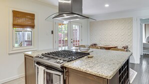 A kitchen with a central island, built-in oven, and a stainless steel range hood. - 1 Mi to Smu: Home w/ Outdoor Entertainment (Dallas)