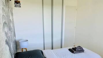 Una camera d'albergo con un letto, una lampada e una parete con persiane verticali.