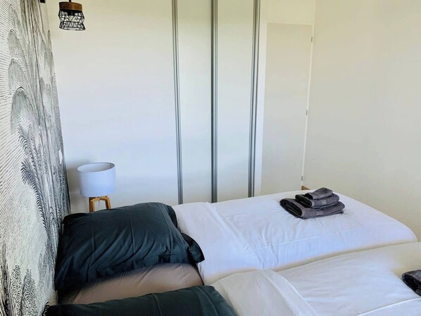 A hotel room with a bed, a lamp, and a wall with vertical blinds.