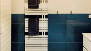 A bathroom with a white towel rack, a dark blue tiled wall, and a white sink.
