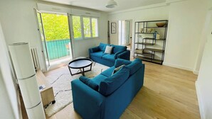 A spacious living room with a blue sectional sofa, a small round table, and a built-in shelving unit.