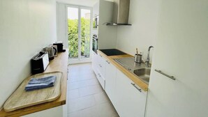A modern kitchen with a large window, a built-in oven, and a stainless steel sink.