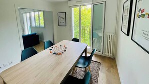 A modern, well-lit room with a large table, blue chairs, and a glass door leading to a balcony.
