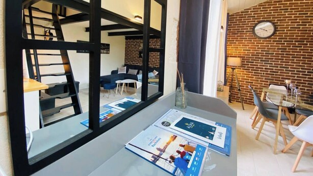 A modern interior with a dining area, a brick wall, and a large window.