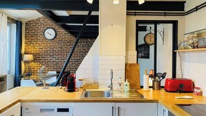 A modern kitchen with a wooden countertop, a built-in dishwasher, and a brick wall.