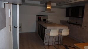 A modern kitchen with a bar area, wooden flooring, and a built-in stove.