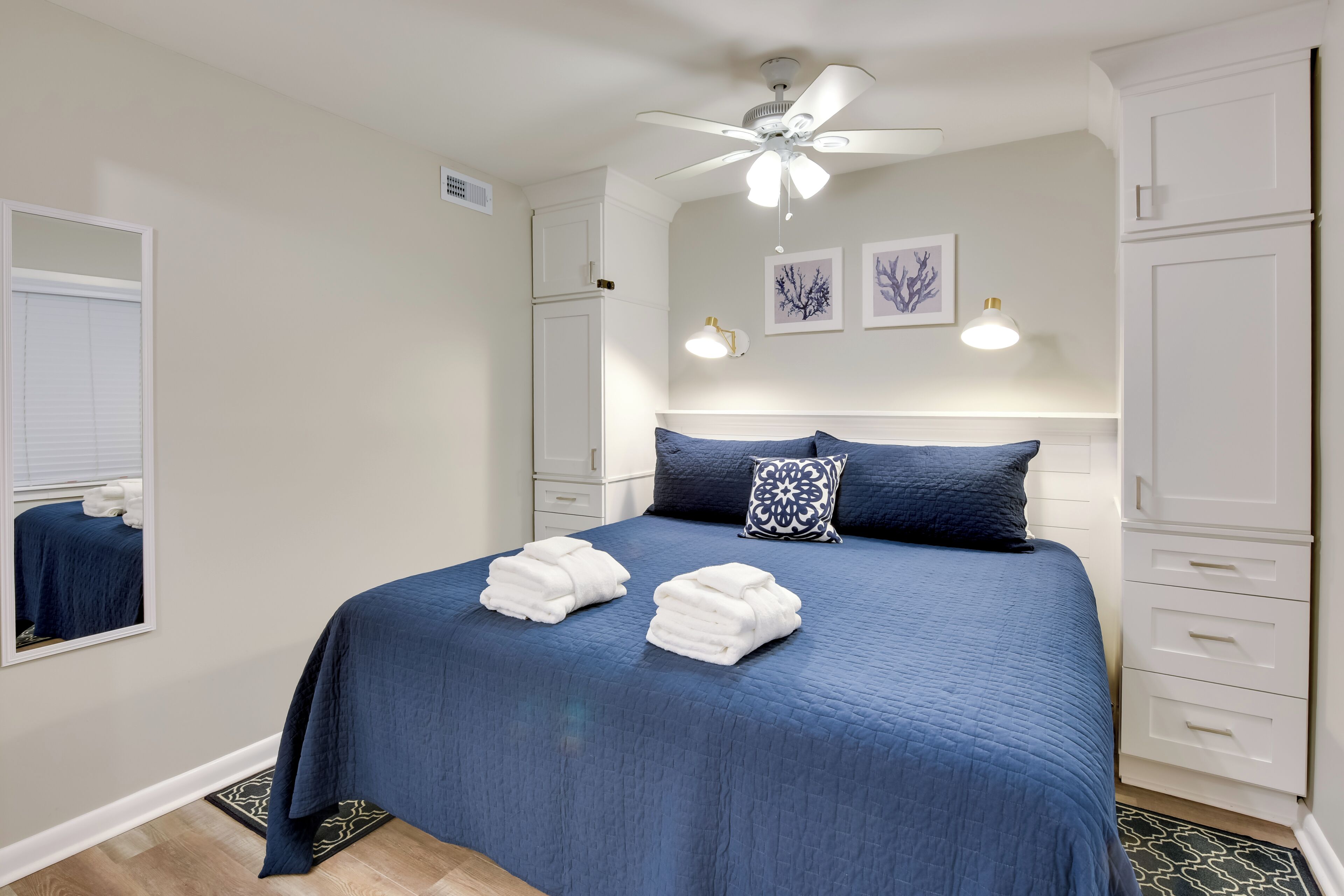 Un dormitorio con una cama grande, armarios blancos, ventilador de techo y luces en la pared.